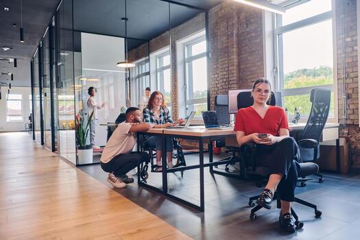 A diverse group of business professionals collaborates in a modern startup coworking center, utilizing a mix of paper-based and technological tools such as mobile phones and computers to collectively photo