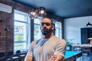 An African American businessman posing with crossed arms, exuding confidence and empowerment within the modern business setting of a startup coworking center. photo