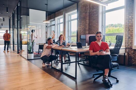 A diverse group of business professionals collaborates in a modern startup coworking center, utilizing a mix of paper-based and technological tools such as mobile phones and computers to collectively photo