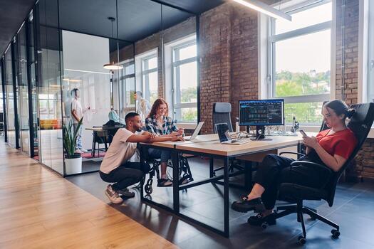 A diverse group of business professionals collaborates in a modern startup coworking center, utilizing a mix of paper-based and technological tools such as mobile phones and computers to collectively photo