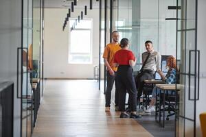 A business group, including an African American businessman in a wheelchair, collaborates within a modern glass office, actively engaged around a computer and laptop, collectively solving diverse photo