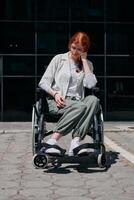 In front of a modern corporate building, a young woman sitting in a wheelchair confidently, symbolizing empowerment, inclusivity, and the strength to overcome challenges in the business world photo
