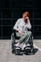 In front of a modern corporate building, a young woman sitting in a wheelchair confidently, symbolizing empowerment, inclusivity, and the strength to overcome challenges in the business world photo