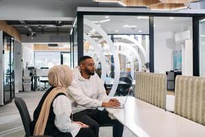 In a modern office setting, an African American businessman and his Muslim colleague, wearing a hijab, engage in collaborative discussions, tackling various business tasks and solving problems photo