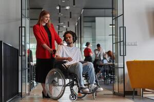 A group of young business people in a modern glass-walled office captures the essence of diversity and collaboration, while two colleagues, including an African American businessman in a wheelchair photo