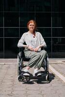 In front of a modern corporate building, a young woman sitting in a wheelchair confidently, symbolizing empowerment, inclusivity, and the strength to overcome challenges in the business world photo