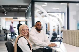 In a modern office setting, an African American businessman and his Muslim colleague, wearing a hijab, engage in collaborative discussions, tackling various business tasks and solving problems photo
