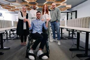 Young businessmen in a modern office extend a handshake to their business colleague in a wheelchair, showcasing inclusivity, support, and unity in the corporate environment. photo