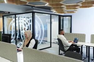In a modern office setting, an African American businessman and his Muslim colleague, wearing a hijab, engage in collaborative discussions, tackling various business tasks and solving problems photo