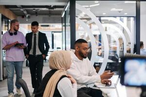 In a modern office setting, an African American businessman and his Muslim colleague, wearing a hijab, engage in collaborative discussions, tackling various business tasks and solving problems photo