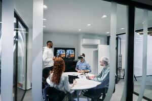 A diverse group of businessmen collaborates and tests a new virtual reality technology, wearing virtual glasses, showcasing innovation and creativity in their futuristic workspace photo