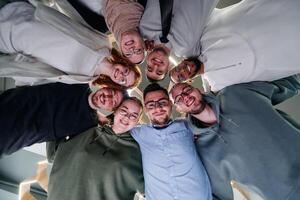 In a modern office, a group of young business professionals is captured in a warm and embracing hug, reflecting the spirit of unity, collaboration, and shared success in their dynamic workplace. photo