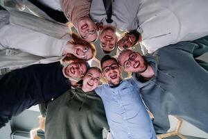 In a modern office, a group of young business professionals is captured in a warm and embracing hug, reflecting the spirit of unity, collaboration, and shared success in their dynamic workplace. photo