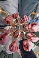 A group of cheerful young people gathered in a circle, pointing at the camera from a low-angle perspective. photo