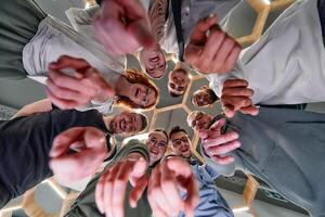 A group of cheerful young people gathered in a circle, pointing at the camera from a low-angle perspective. photo