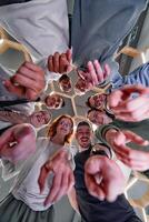A group of cheerful young people gathered in a circle, pointing at the camera from a low-angle perspective. photo