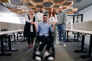 Young businessmen in a modern office extend a handshake to their business colleague in a wheelchair, showcasing inclusivity, support, and unity in the corporate environment. photo