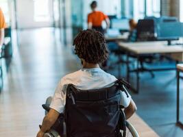 A wheelchair-bound businessman seamlessly navigates through contemporary business offices, epitomizing resilience and adaptability as he maneuvers his way with ease, challenging stereotypes and photo