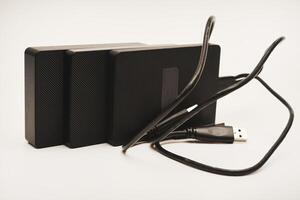 Hard drives a white background. Modern data storage devices with USB wires. photo