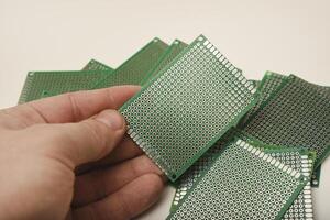 The printed circuit board is in your hand. A green breadboard for electronics. photo