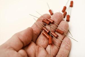 Old resistors in your hand. Resistors with axial terminals. Elements of electronics. photo