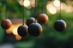 Decorative wooden spheres suspended in a tranquil garden during golden hour with blurred background lights photo