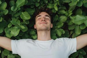 Young man relaxing on lush green foliage, enjoying nature in a serene outdoor setting photo