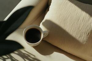 Warm cup of coffee rests on a cozy beige cushion in the soft morning light photo