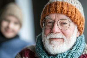 Elderly man with white beard wearing stylish knit hat and scarf enjoys cozy atmosphere indoors with smiling companion in background photo