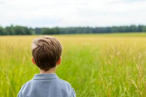 Child gazing at vast green field under cloudy sky during late afternoon photo