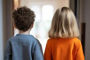 Children standing together in a brightly lit hallway while looking towards an open space outside photo