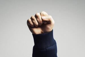 Fist raised in solidarity against a neutral background during an empowerment event or campaign photo