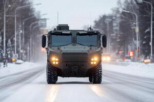 Military vehicle navigating a snow-covered road during winter in an urban area at dusk photo
