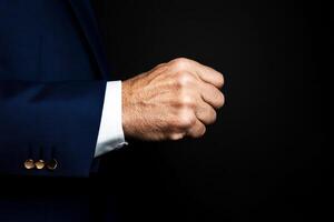 Professional man in blue suit making a fist against a dark background to convey determination and strength in a business setting photo