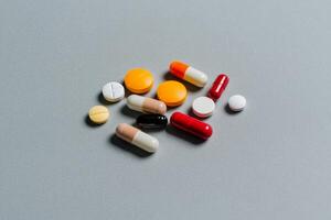 Various types of capsules and tablets scattered on a flat surface in a clinical setting photo