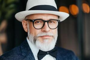 Stylish older man wearing glasses and a bow tie poses confidently in a modern cafe setting during daytime photo