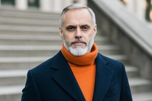 Mature man in stylish winter attire stands confidently on urban steps in soft sunlight during autumn afternoon photo