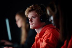 Focused young gamers engaged in competitive gaming in a dark environment during an esports event photo