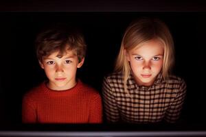 Children engaged in intense focus while watching a screen, highlighting curiosity and intrigue in a darkened room photo