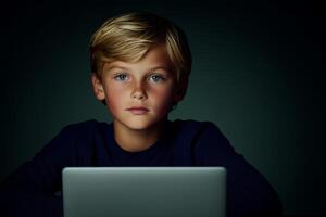 Young child focused on laptop screen in a dimly lit room, illustrating concentration and curiosity photo