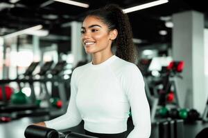 A young woman with curly hair exercises with a smile in a well-lit gym. She is surrounded by various fitness equipment, showcasing a lively workout atmosphere photo