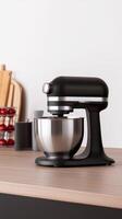 Black kitchen mixer on a wooden countertop with various kitchen utensils in a cozy, modern kitchen setting photo