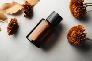 Essential oil bottle surrounded by dried flowers on a light surface with a calm and serene atmosphere photo