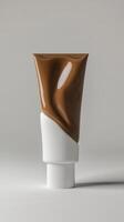 Brown cosmetic cream tube standing upright on gray background showcasing elegant design and smooth texture photo