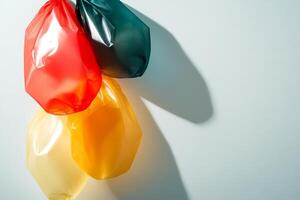 Hanging plastic bags in green, red, and yellow create a colorful display against a light background photo