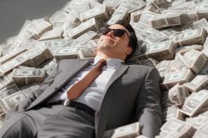 Businessman lying on pile of money , showcasing wealth and success in a contemporary environment photo
