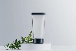 Clear glass container placed on a white pedestal with green foliage beside it in a minimalist setting photo