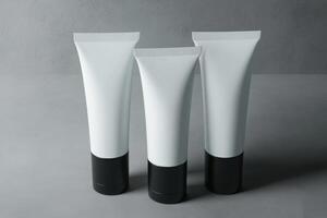 Three minimalist cosmetic tubes arranged on a grey surface showcasing a sleek and modern design photo