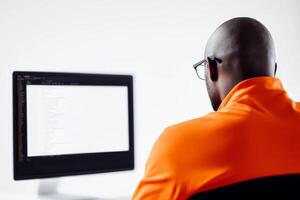 Focused individual in orange shirt working on computer photo