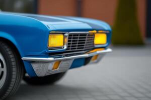 Classic blue car close-up showcasing front grille and headlights in a modern urban setting photo